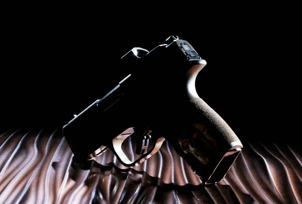stock image Human skull on the pistol grip of a ghost gun silhouette on a broinze wavy sufrace