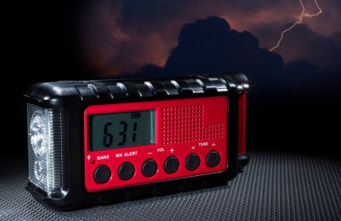 İçinde el feneri ve saat bulunan kırmızı hava durumu radyosunun arkasındaki elektrik fırtınası..