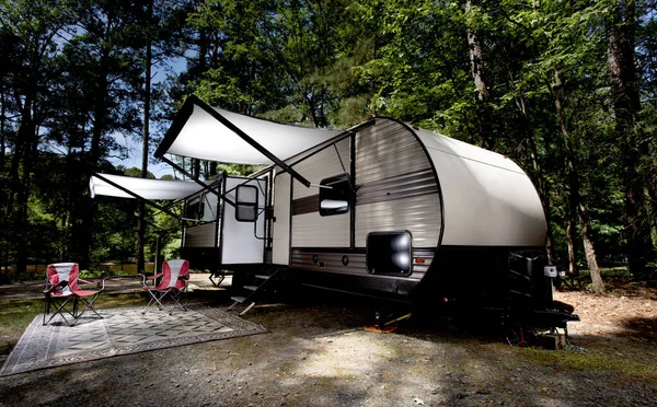 Campsite in the middle of the day with a camper trailer\'s awnings out