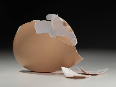 Siyah arka planlı beyaz bir yüzeyde kırılan tavuk yumurtası..