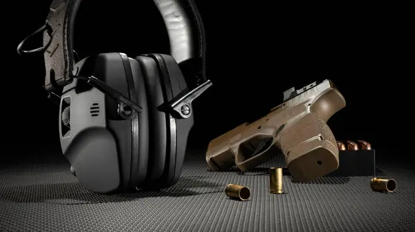 Electronic hearing protection that has a handgun and 9 mm ammo nearby