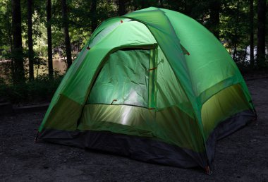 Sırt çantalı çadır, arkasında parlak bir göl bulunan eski bir kamp alanında aydınlandı..