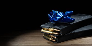 Mavi hediye yayı yüksek kapasiteli saldırı tüfeği şarjörleri ile dolu sol tarafta siyah bir arka planda yazı için yer var..