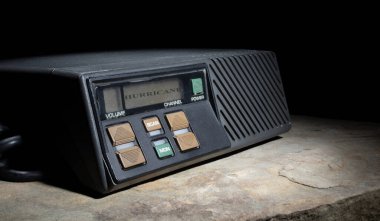 Karanlık bir arkaplanda, LCD ekranında kasırga uyarısı olan bir alıcı verici.