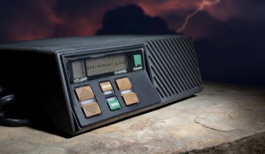 Karanlık bir arkaplanda, LCD ekranında kasırga uyarısı olan bir alıcı verici.