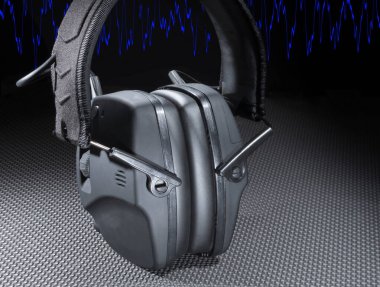 Mavi sinüs dalgası, çekim sırasında veya iş sırasında işitme koruması için elektronik bir kulaklığın arkasından geçiyor.