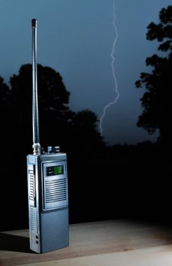 Dokuzuncu kanaldaki telsiz frekansları için iki yönlü telsiz ışığı arka plandaki ağaçların altına vururken masanın üzerinde dinleniyor..