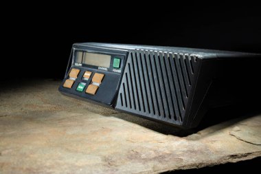 Koyu arkaplanı olan taştan bir yüzeyde iki yönlü VHF radyo..