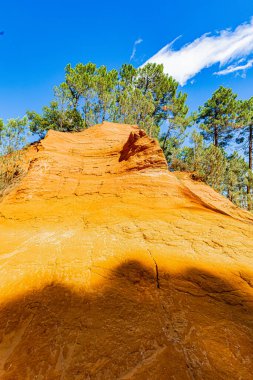 24 Eylül 2025 'te Fransa' nın Vaucluse Bölümü 'ndeki Roussillon' da, kan ve altın renkli yolların ve uçurumların jeolojik manzarası olan Sentier des Ocres 'in bulunduğu yer. Güneşli bir Provencal günü sunuyor bir dekoru toprak ve gök mavisi.