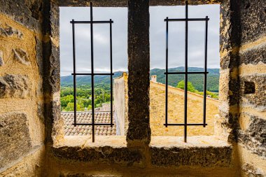 23 Eylül 2025 tarihinde Fransa 'nın Drome bölgesinde bulunan Le Poet Laval adlı ortaçağ tünemiş köyünün mineral mimarisi. Taştan duvardaki bir delikten köyün görüntüsü.