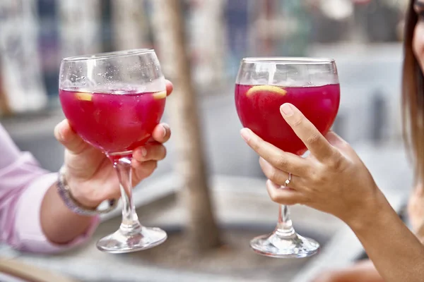 Stock image Crop anonymous couple in love clinking glasses with red refreshing cocktails while celebrating anniversary in street cafe in summer