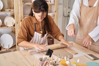 Çömlek atölyesinde önlüklü arkadaşlar kil hazırlıyor. El sanatları sınıfı. 