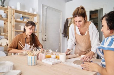 Çömlek atölyesinde önlüklü arkadaşlar kil hazırlıyor. El sanatları sınıfı. 