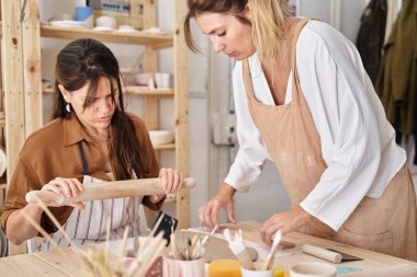 Çömlek atölyesinde önlüklü arkadaşlar kil hazırlıyor. El sanatları sınıfı. 