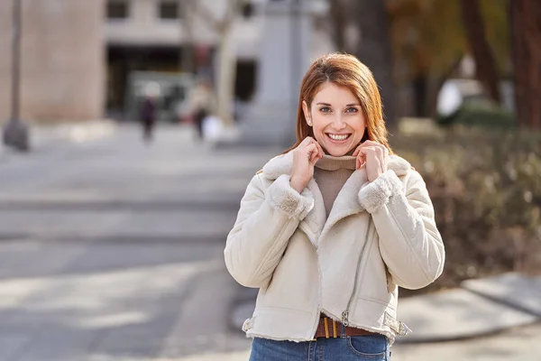 路上で屋外でポーズをとりながらカメラを見ながら笑顔でジャケットを着たスタイリッシュな女性 — ストック写真