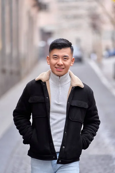 stock image Asian man looking at camera and smiling while standing outdoors on the city street.