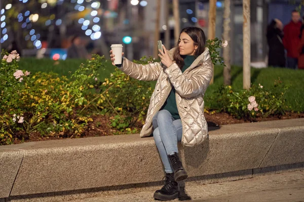 携帯電話を使ってコーヒーを屋外で撮る女性 冬と技術の概念 — ストック写真