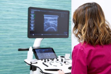 Doctor consulting something on ultrasound equipment while working in a medical center. Concept of medicine and health.