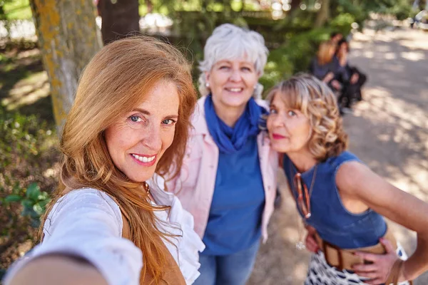 グループでセルフィーをしながら携帯電話で楽しい時間を過ごしている女性の陽気なトリオ — ストック写真