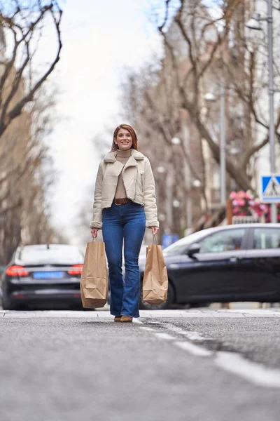 Woman smiling while walking on the city street with shopping bags. Shopping and urban lifestyle concept.