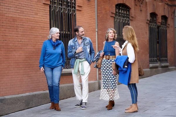 60代の4人の親しい友人が通りを歩き おしゃべりし 一緒に笑って お互いの会社や美しい街の観光を楽しんでいます — ストック写真