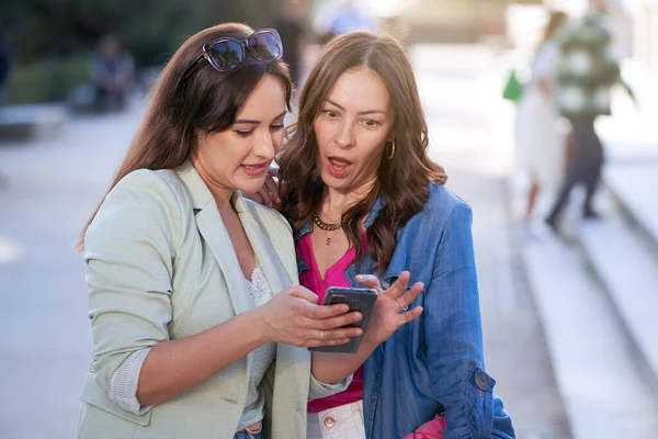 Twee Vrouwen Die Geschokt Kijken Terwijl Naar Een Mobiele Telefoon — Stockfoto