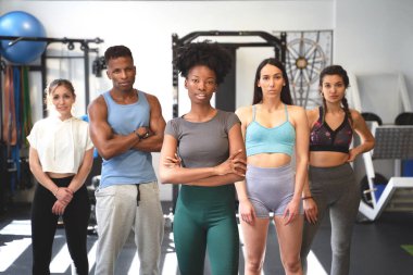 Spor salonunda birlikte poz verirken kameraya bakan bir grup sportif insan. Spor ve sağlıklı yaşam tarzı kavramı.