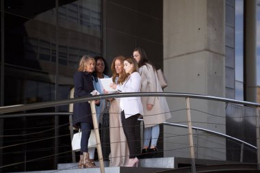 Bir grup profesyonel kadın girişimci açık hava iş alanındaki tablet bilgisayarda finansal istatistikleri tartışıyor ve verileri analiz ediyorlar.