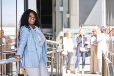 Ofis binasının dışında poz verirken kameraya bakan profesyonel bir iş kadını. İş konsepti.