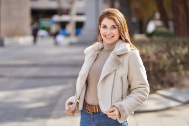 Güzel kızıl saçlı kadın model kışın parkta poz veriyor.