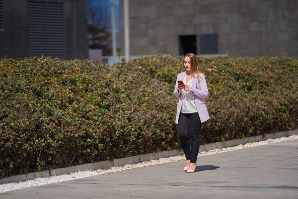 仕事帰りに携帯電話でおしゃべりしながら散歩する若い実業家の女性 — ストック写真