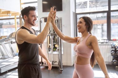 Esmer fitness çifti spor salonundaki çalışmalarını bitirdikten sonra çok mutlu bir şekilde beşlik çakıyor.