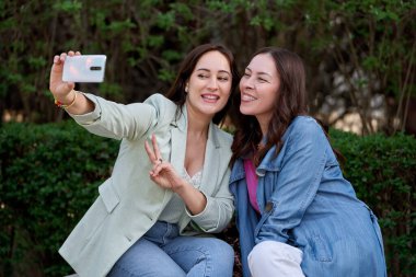 Dışarıda cep telefonuyla selfie çeken iki kadın. Teknoloji ve arkadaşlık kavramı.