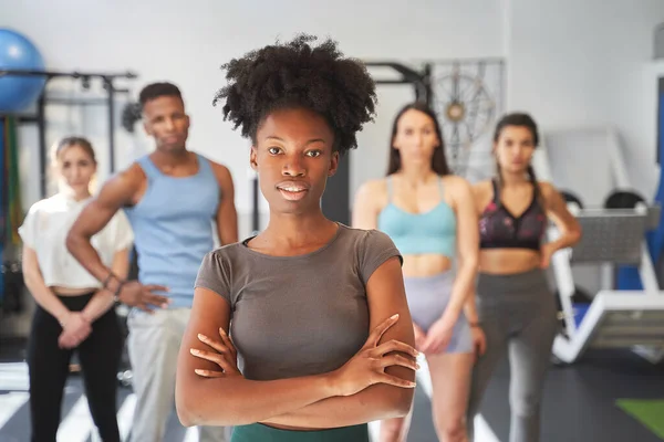 Spor salonunda bir grup sporcunun önünde poz verirken kendine güvenen bir kadın. Spor konsepti.