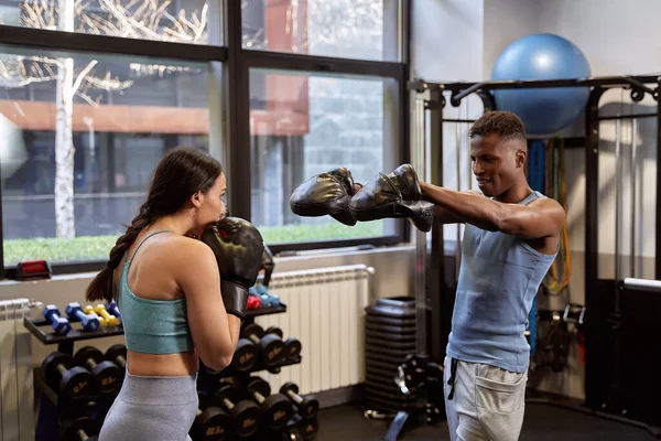 stock image Intense Boxing Workout: African-American Man and Caucasian Woman Wearing Gloves in Gym