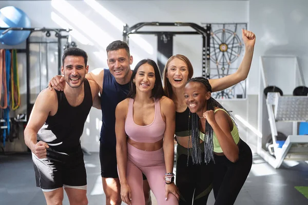 multicultural fitness group posing and smiling looking at the camera in the gym