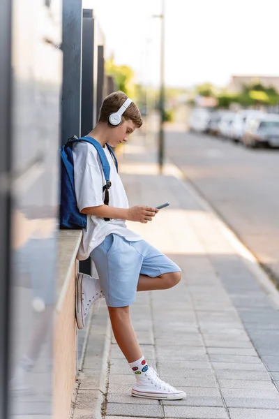 Εφηβικό Αγόρι Που Χρησιμοποιεί Κινητό Τηλέφωνο Και Ακουστικά Ενώ Χαλαρώνει — Φωτογραφία Αρχείου
