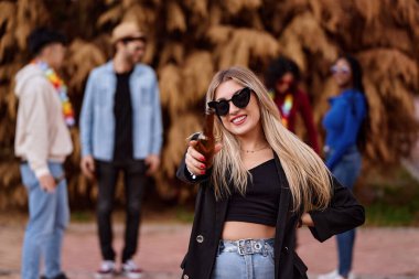 Elinde bira şişesi olan bir kadın dışarıda eğlenirken gülümsüyor. Parti ve kutlama konsepti.