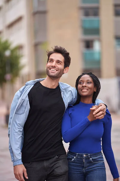 stock image Multi-ethnic couple smiling as they walk down the street together looking at infinity. Relationship concept.