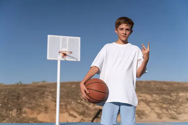 Anak Muda Memegang Bola Basket Sementara Berpose Lapangan Luar Ruangan — Stok Foto