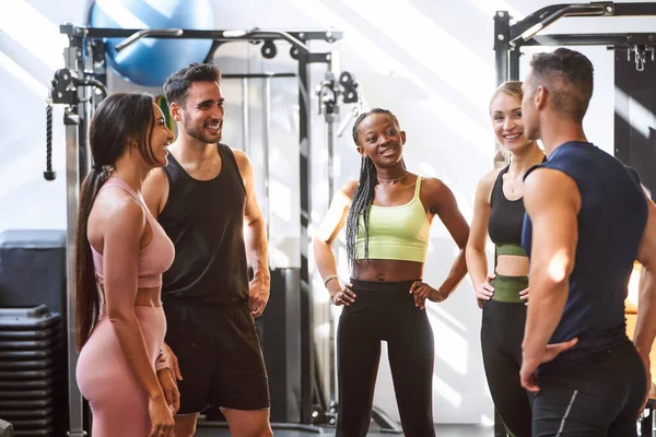 Group of fitness people talking after training together at the gym. Sports concept.
