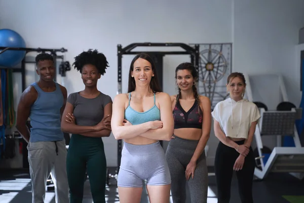 Spor salonunda takımın önünde duran kendinden emin bayan antrenör. Spor konsepti.
