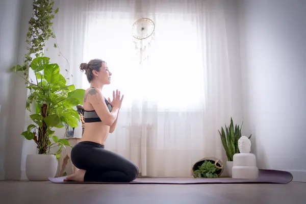 Evde yoga minderinde oturmuş meditasyon yapan bir kadın. Spor konsepti.