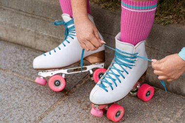 Close-up detail of a skaters hands tying the laces of a pair of quad roller skates.  clipart