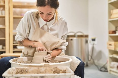 Çömlekçi tekeriyle çömlek atölyesinde çalışan kadın seramisyen.