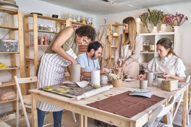 Önlüklü bir grup insan bir atölyede seramik el sanatları yapıyor. Hobi ve zanaat konsepti.