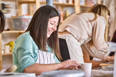 Bir atölyede el yapımı çömlek yaparken gülümseyen bir kadın. Hobi ve el işi konsepti.
