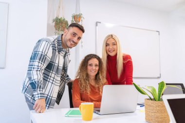 Profesyonel iş ekibi ofiste çalışırken kameraya bakıp gülümsüyor. İş konsepti.