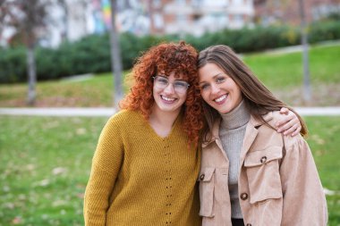 Dışarıda poz verirken gülümseyen genç bayan arkadaşlar. Arkadaşlık kavramı.