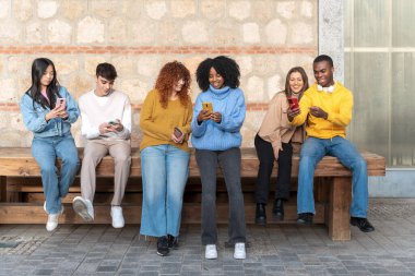 Group of multiethnic friends using their mobile phones together. Technology and friendship concept.